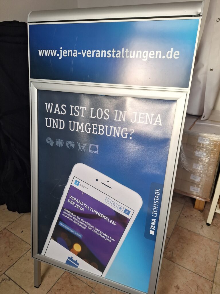 Ein Kundenstopper für A1-Plakate, auf dem oberhalb die URL von www.jena-veranstaltungen.de steht.